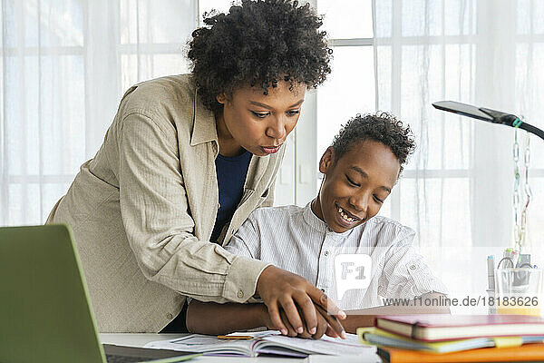 Mother helping son doing homework at home