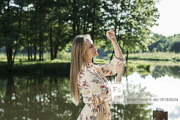 Young woman with eyes closed gesturing in front of river