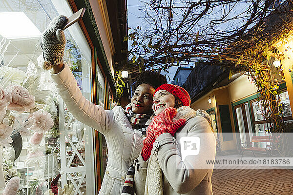 Multiracial friends taking selfie through smart phone at street