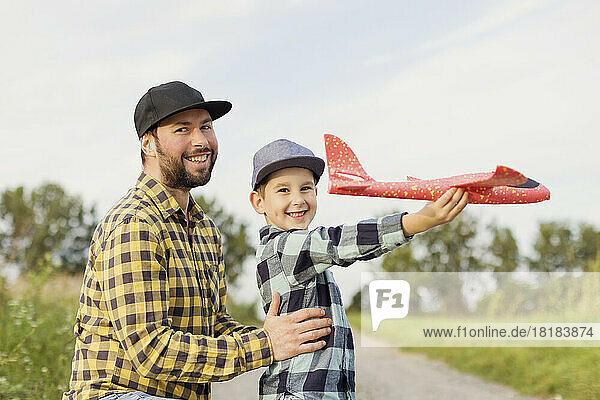Smiling father and son with toy airplane wearing plaid shirts
