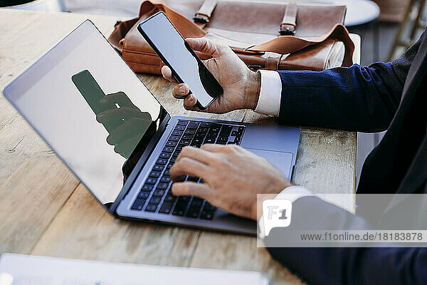 Businessman working with smart phone and laptop on table