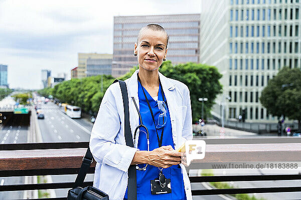 Smiling healthcare worker with smart phone in city