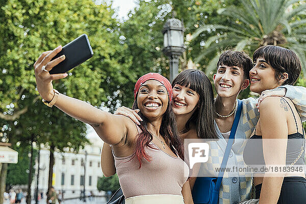 Glückliche Frau mit Freunden  die im Park ein Selfie mit dem Handy machen