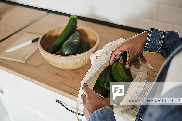 Hands of woman removing vegetables from bag at kitchen counter