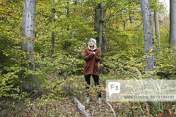 Reife Frau steht am Wochenende inmitten von Bäumen im Wald