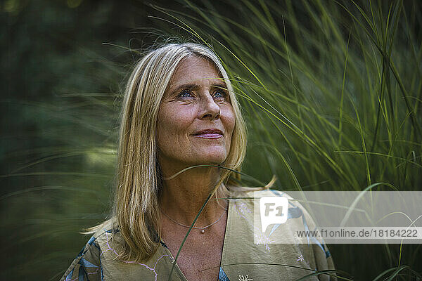 Thoughtful mature woman with blond hair in garden