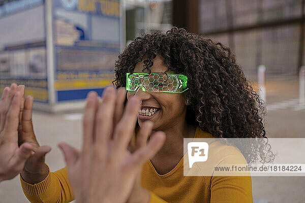 Happy young woman wearing smart glasses giving high-five to man