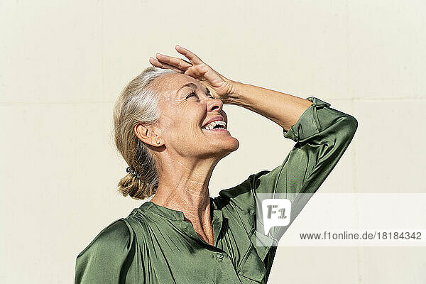 Happy mature woman shielding eyes on sunny day