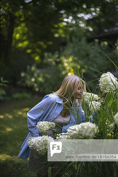 Mature woman smelling flowers in garden