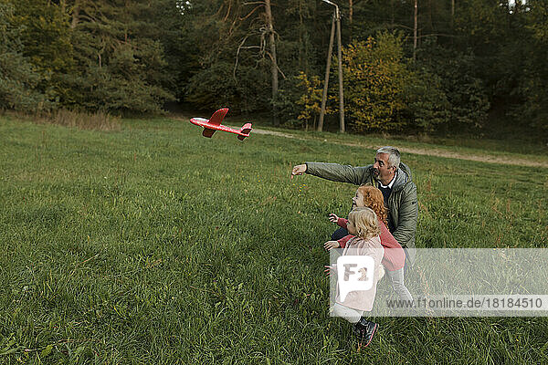 Großvater und Enkel spielen mit Flugzeugspielzeug auf Gras