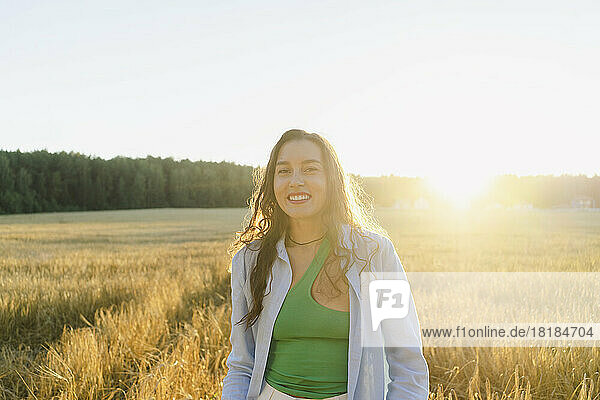 Happy woman standing at field at sunset