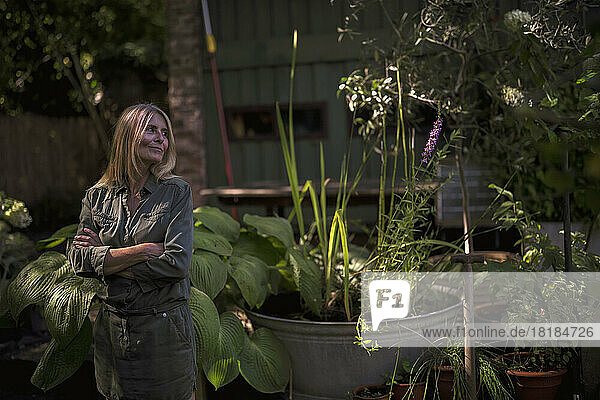 Smiling woman standing with arms crossed in garden