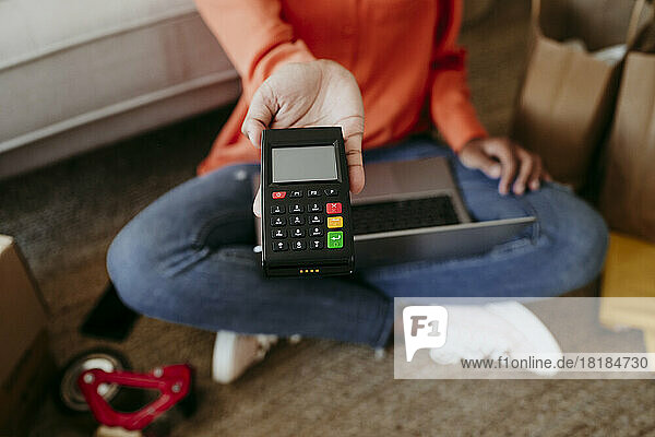 Hand of businesswoman holding credit card reader at home office
