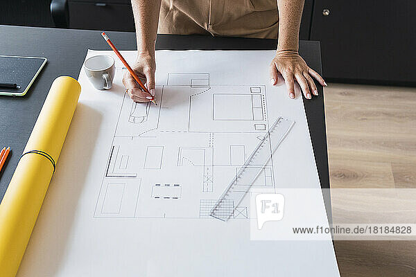Architect working on blueprint leaning on table