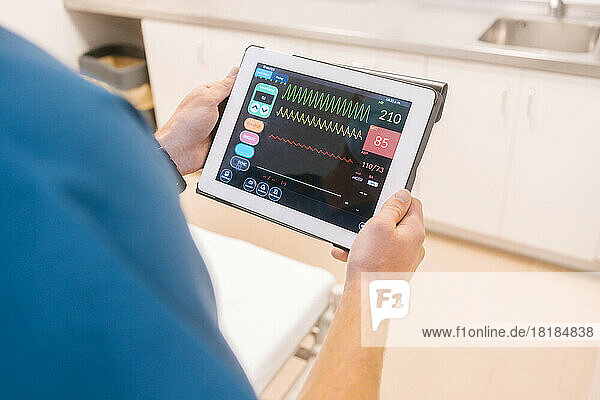 Hände eines Arztes untersuchen Daten auf einem Tablet-PC im Krankenhaus