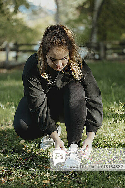 Young woman tying shoe lace in park