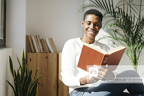 Smiling woman reading book at home