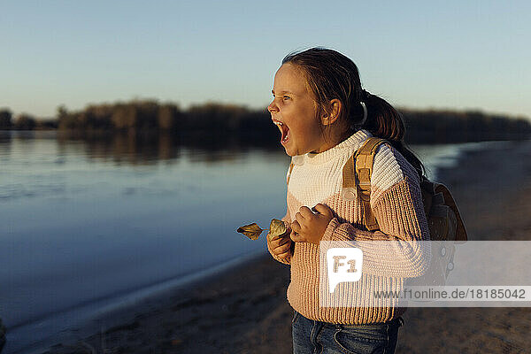 Girl with backpack screaming at beach