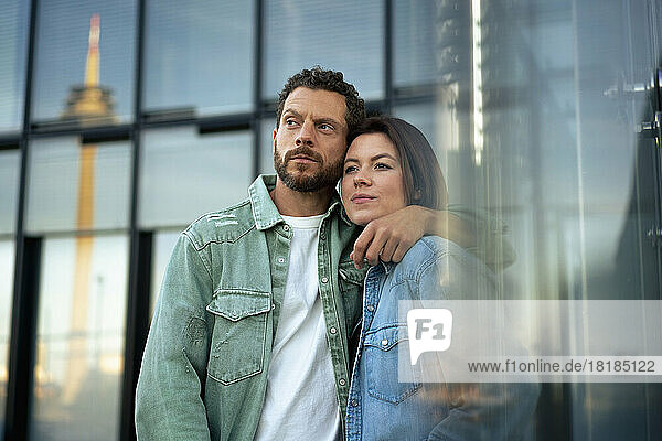 Contemplative man with arm around woman in front of building