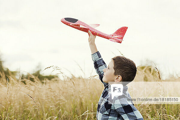 Junge fliegt Spielzeugflugzeug auf dem Feld