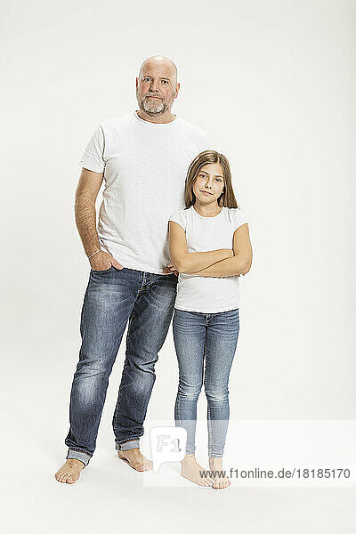 Confident father and daughter against white background