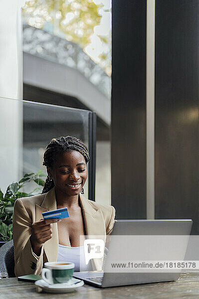 Smiling young businesswoman making credit card payment in cafeteria