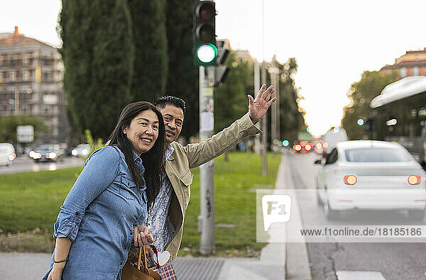 Smiling woman standing by man hailing footpath by street