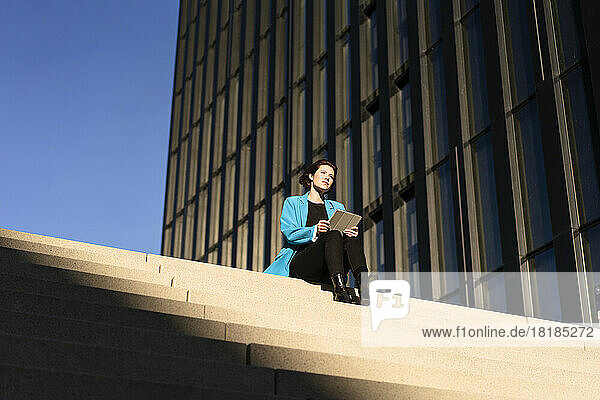 Junge Geschäftsfrau mit Tablet-PC sitzt auf der Treppe