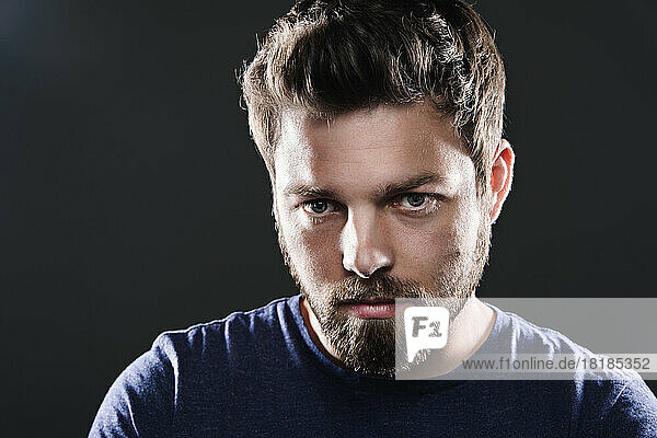 Portrait of sad man with beard in front of black background