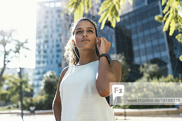 Young woman wearing headphones listening to music in front of building