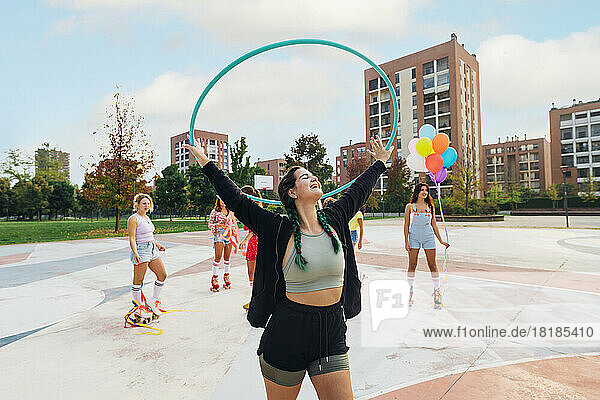 Happy woman holding hoop in front of friends at sports court