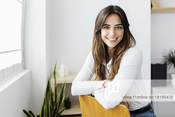 Happy woman sitting on chair at home