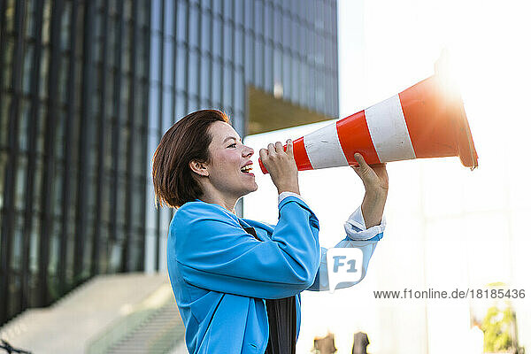 Businesswoman making announcement holding traffic cone
