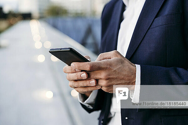 Hands of businessman text messaging through smart phone