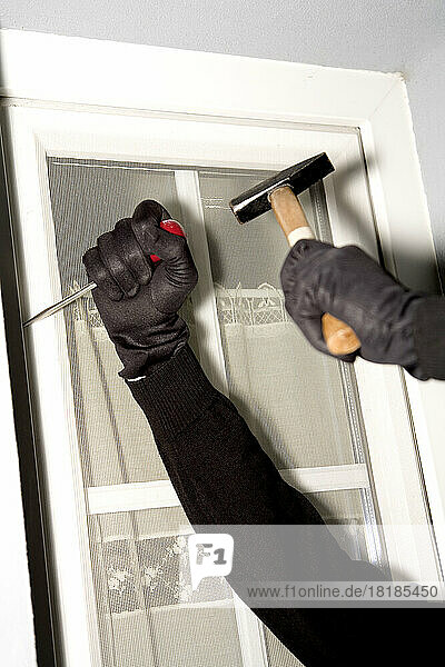Burglary hand with gloves on window  close-up