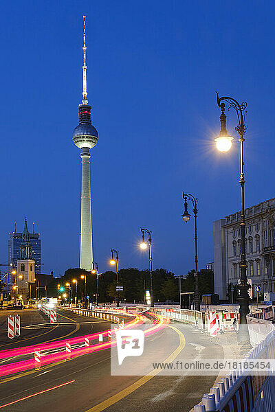 Germany  Berlin  Vehicle light trails stretching along illuminated street at night with Berlin Television Tower in background