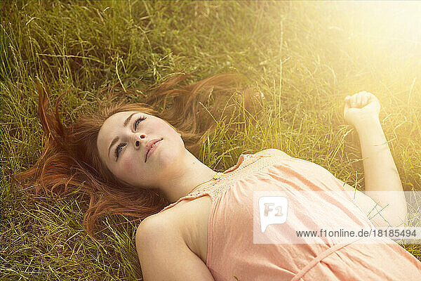 Daydreaming woman lying on a meadow