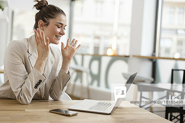 Aufgeregte Geschäftsfrau blickt im Büro auf Laptop