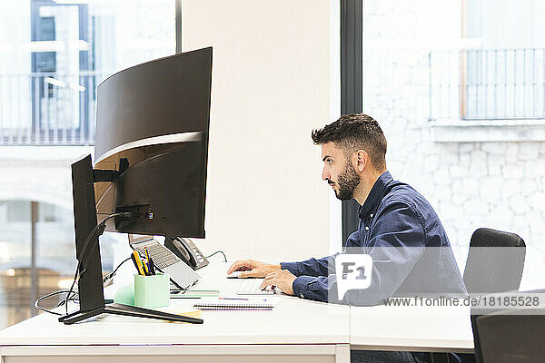 Young businessman working on laptop at desk in office