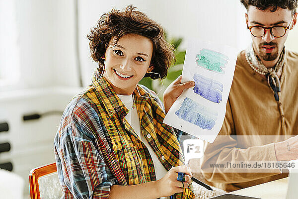Happy illustrator showing watercolor painting by colleague in office