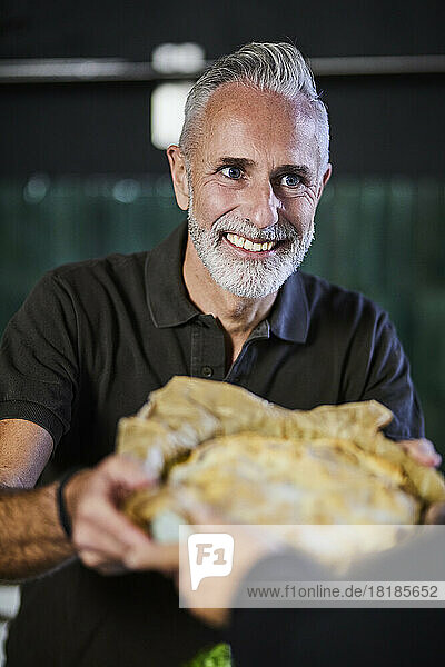 Happy mature man handing over savory pie