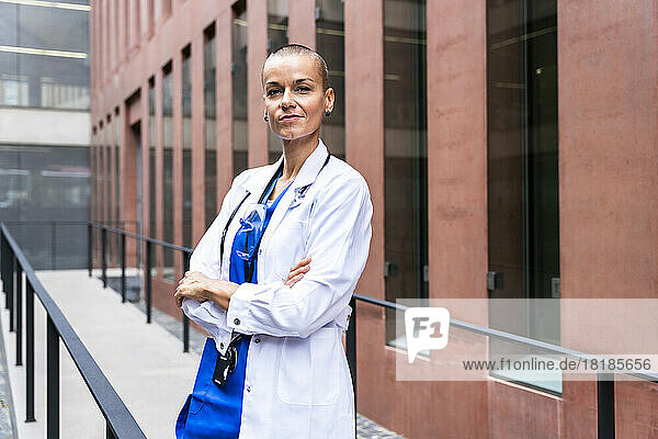 Confident mature nurse with arms crossed outside hospital