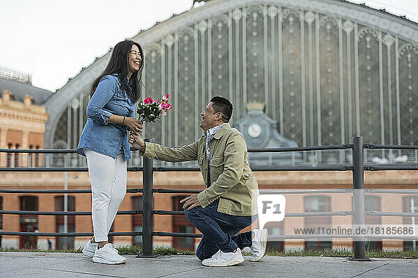 Glücklicher Mann schenkt Frau am Valentinstag Blumen und macht ihr auf dem Fußweg einen Heiratsantrag