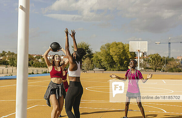 Happy friends playing basketball in sports court