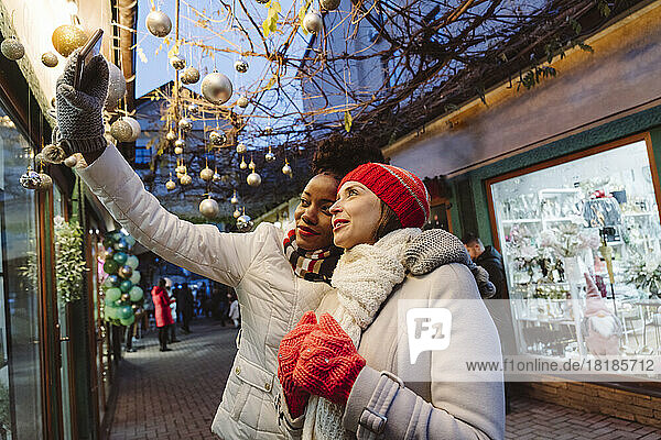 Friends wearing warm clothing taking selfie through smart phone at street