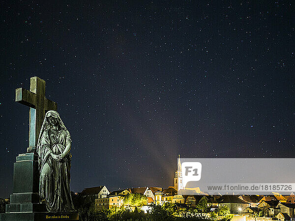 Germany  Bavaria  Nabburg  Tombstone at night with illuminated town in background