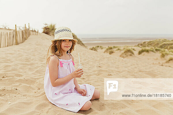Portrait of girl sitting on the beach having a drink