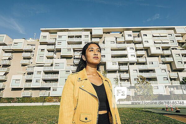 Nachdenkliche junge Frau steht vor einem Wohnhaus