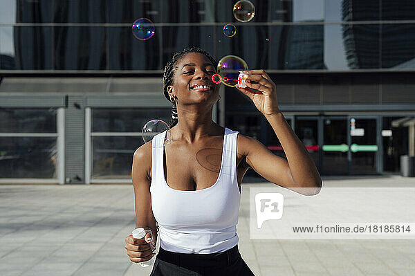 Young woman blowing bubbles outside building