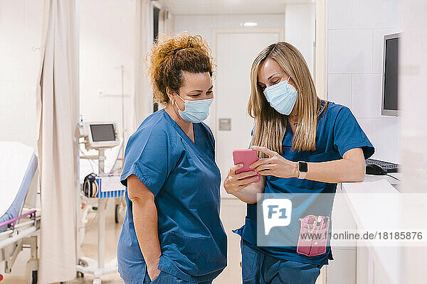 Nurse with colleague using smart phone at hospital